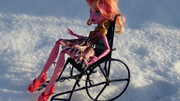 Barbie-nukke istuu pyörätuolissa ulkona.