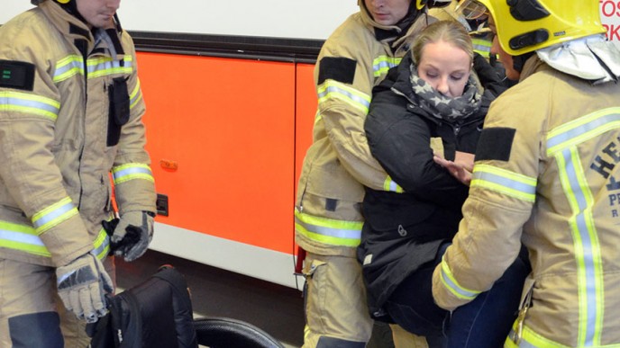 Palomiehet nostavat naisen pyörätuoliin.