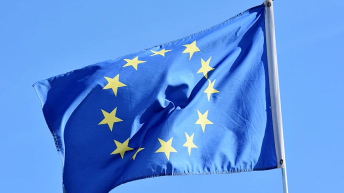 Sininen EU-lippu jossa keltaisia tähtiä ympyrässä liehumassa sinisellä taivaalla.